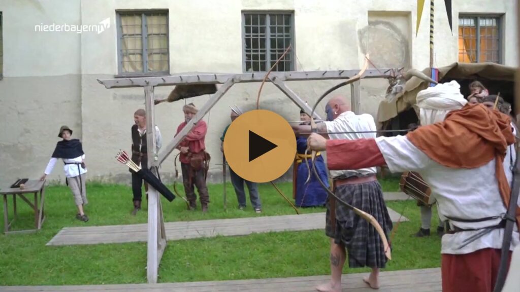 Vorschaubild mit Play-Symbol: Bogenschützen in Gewandung beim Schießen auf dem Mittelalterfest in Arnstorf, aus dem Beitrag von Niederbayern TV; ab Minute 10:45 geht es um die Traditionellen Bogenschützen Arnstorf